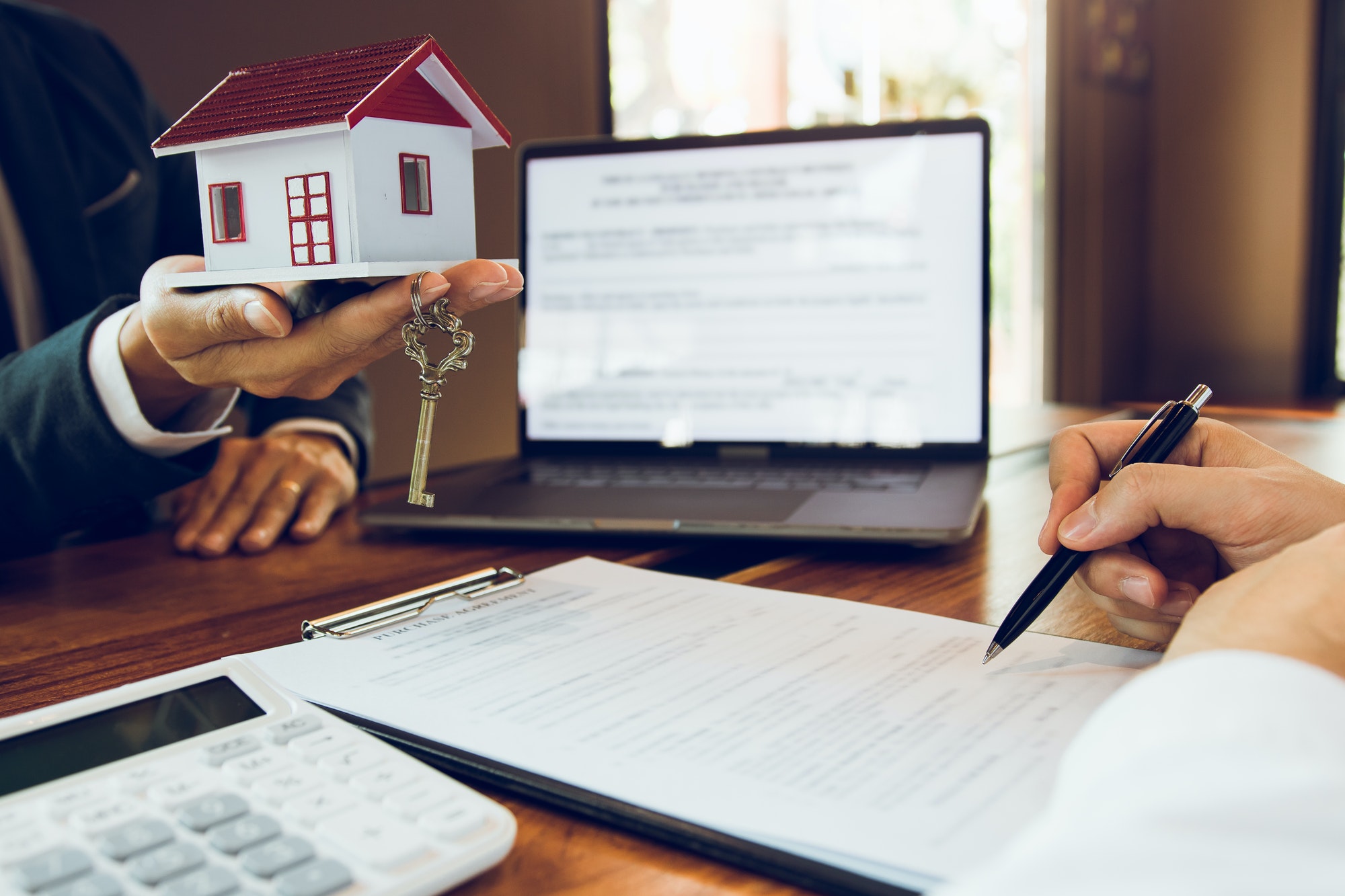 Customer writing signing signature on paper contract with real estate agent with new home concept.